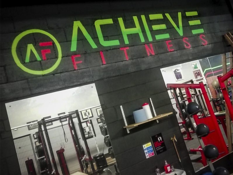 A gym with an office branding sign that says achieve fitness.