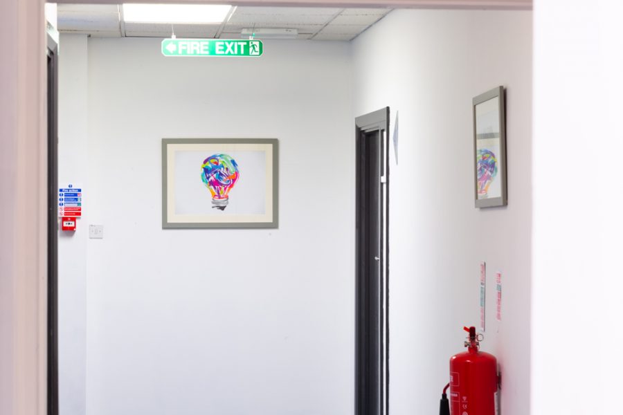 A hallway with an office branding-themed painting and a fire extinguisher.