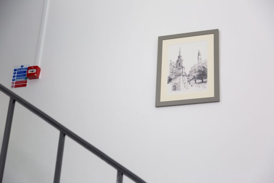 A framed picture showcasing office branding hangs on the wall of a staircase.