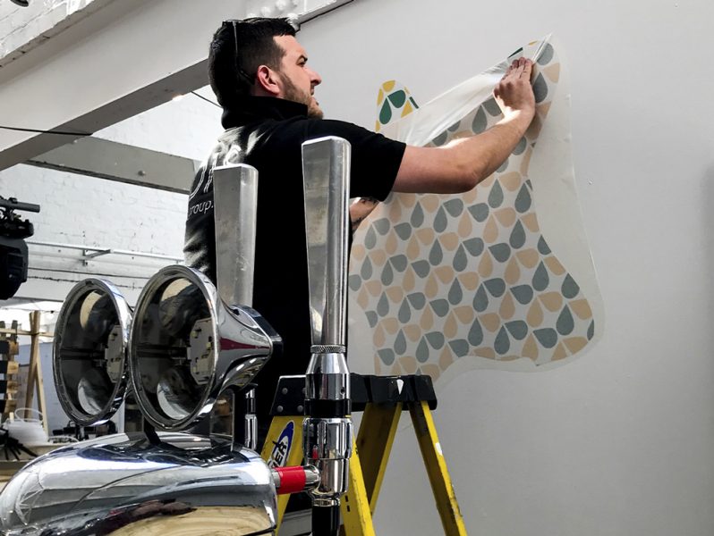 A man is performing office branding by painting a pattern on a wall.