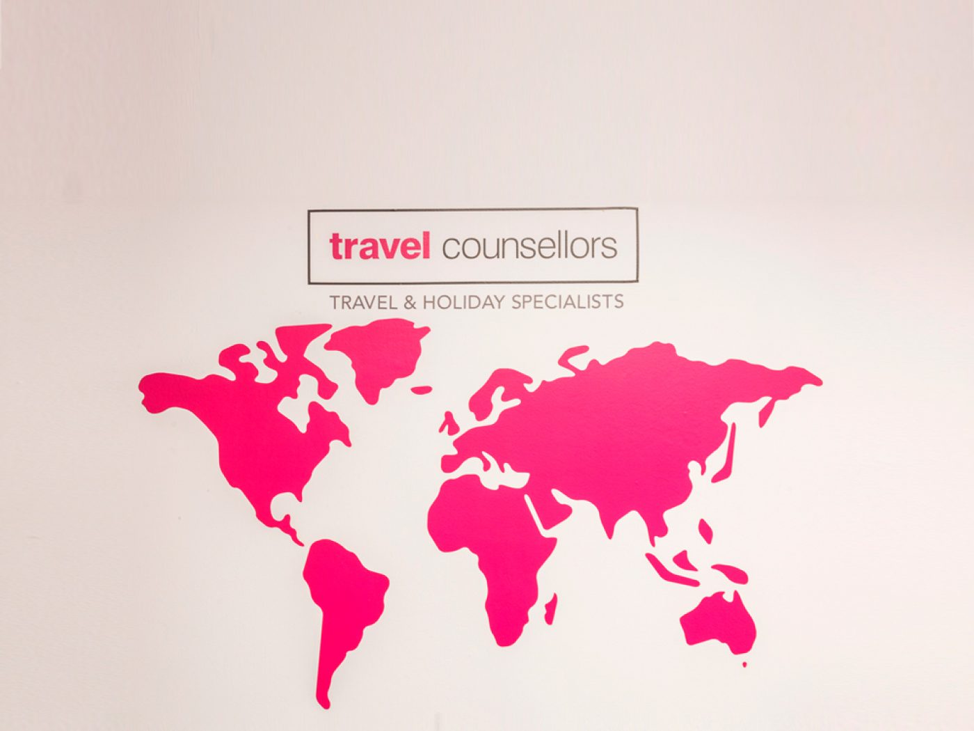 Office branding incorporated into a pink world map showcasing travel counselors.