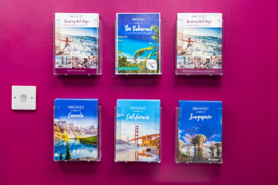 A display of travel books on a pink wall, enhancing office branding.