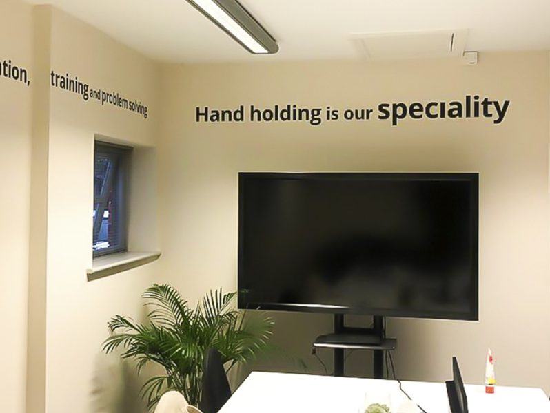 A room with a tv and a wall that says hand holding our specialty.